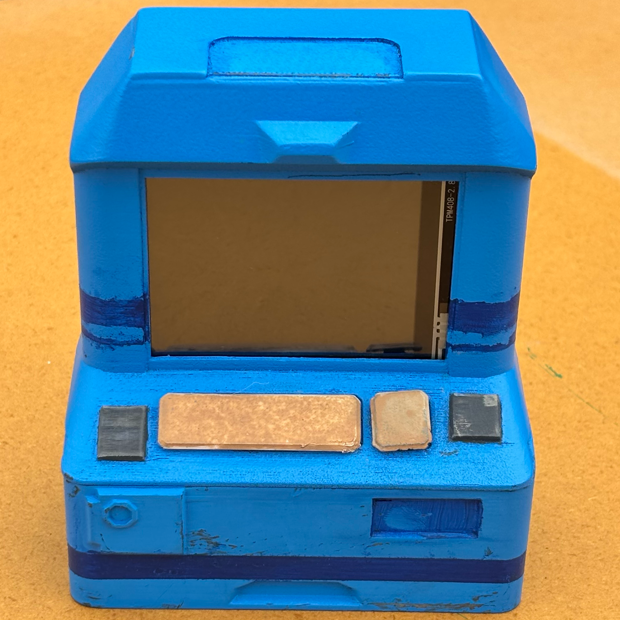 A small blue machine with a screen and 4 buttons below.